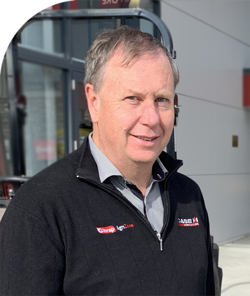 Andrew Giltrap standing outside Giltrap AgriZone dealership with tractors and machinery on display